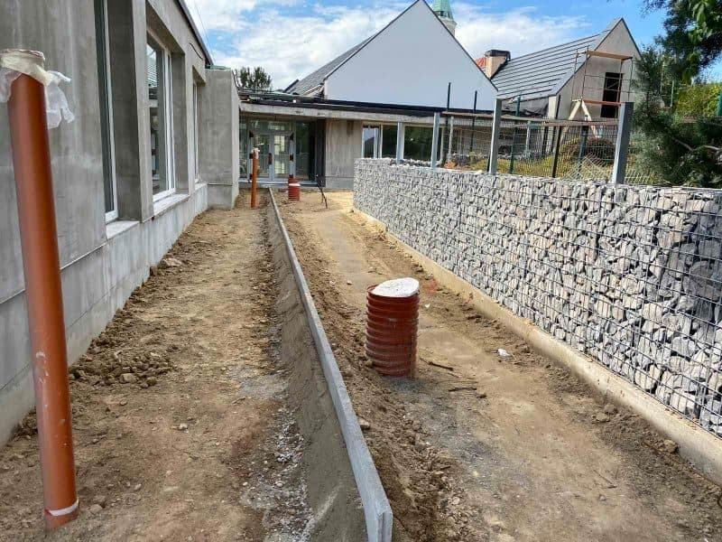 Offener Graben für die Drainage entlang der Hauswand mit verlegtem Rohr